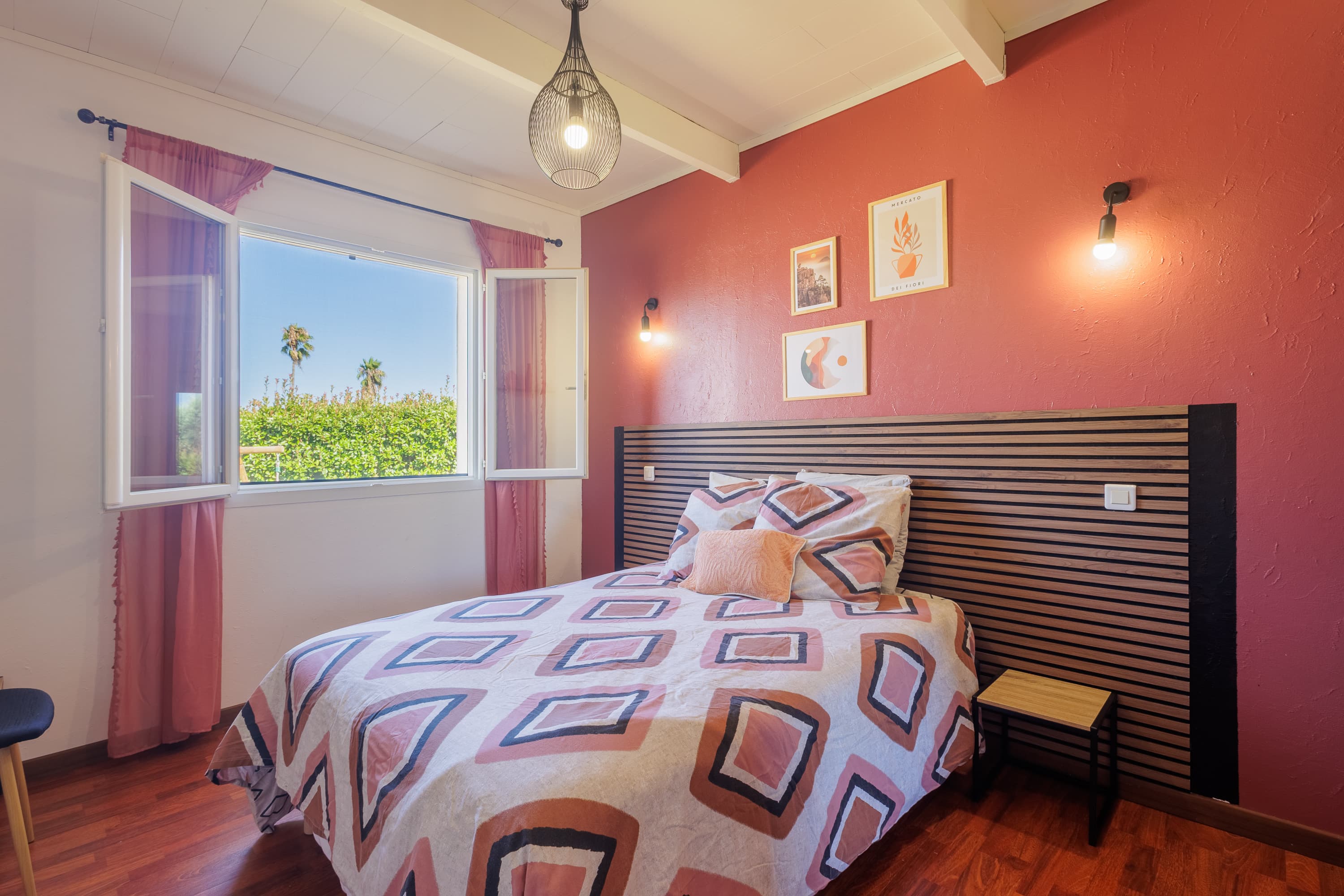 Chambre double aux murs terracotta avec vue sur la verdure