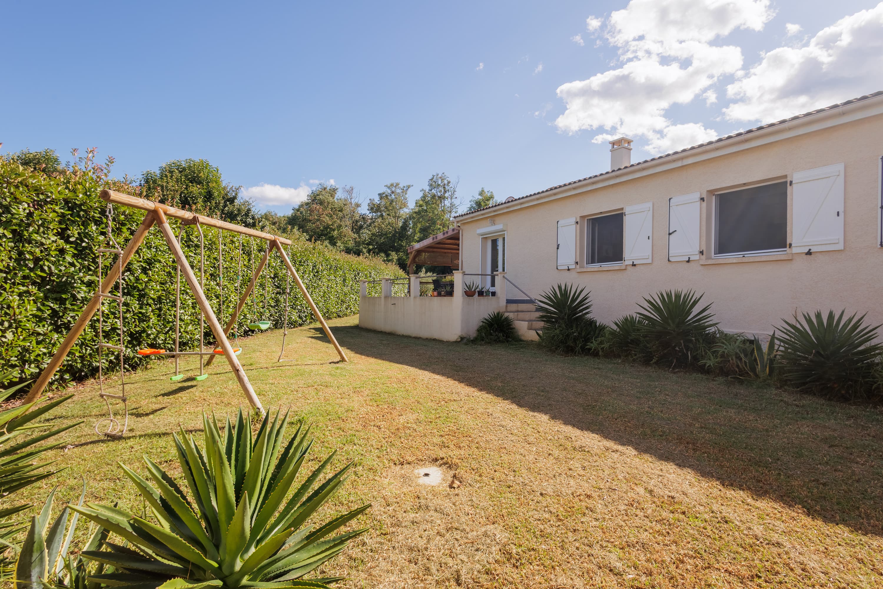 Jardin clos avec aire de jeux pour enfants le long de la villa de plain-pied
